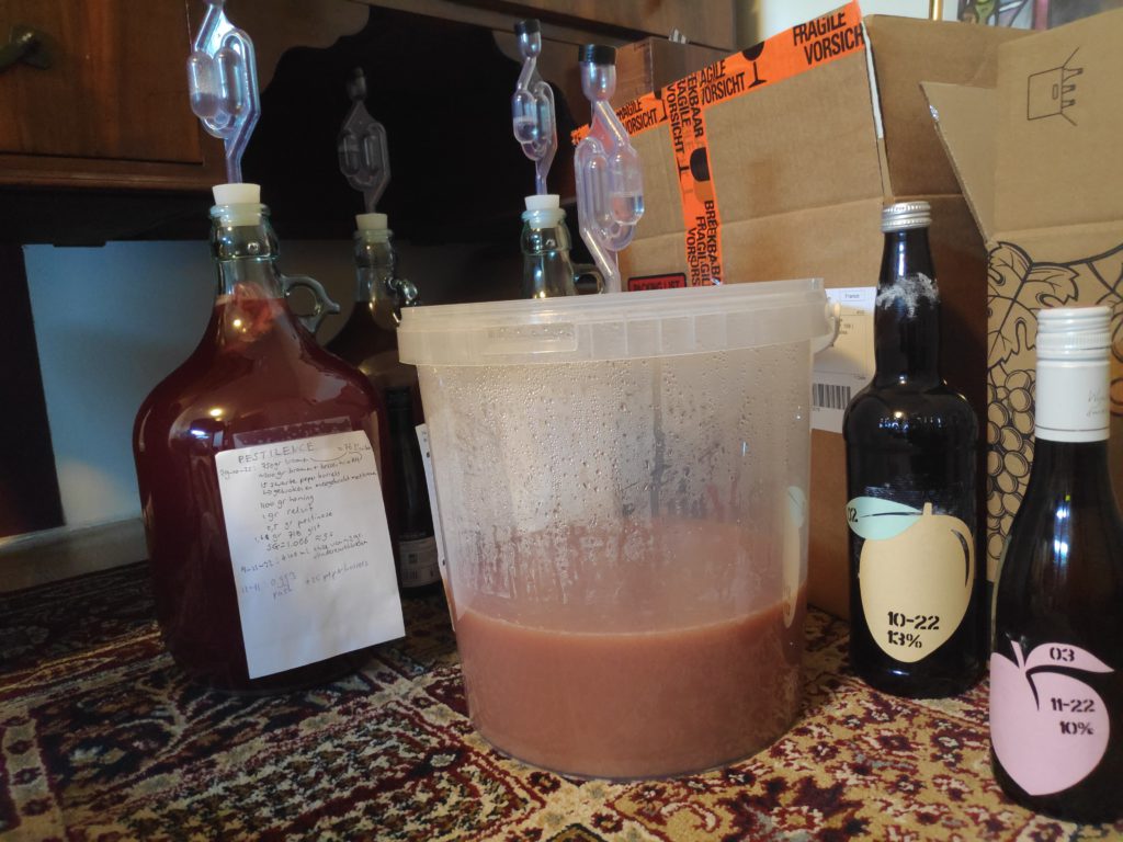An assortment of bottles, and a bucket with a brew fermenting in it.